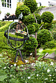 Planted garden bed with armillary sphere and Japanese yew tree
