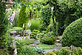 Well-kept ornamental garden with gravel path, a sitting stone and a variety of plants