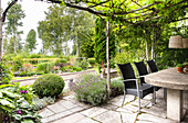 Terrace design with plants and dining table under pergola