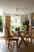 Glass topped dining table with light wood chairs in sunlit dining room