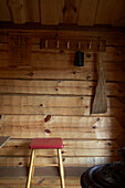 Hand crafted coat hooks with a traditional Swedish broom and 1950s stool in wood hut in Svartadalen, Sweden