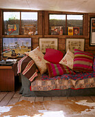 Details a wall of framed images and vinyl records above a traditional sofa displaying a variety of cushions in front of a rug
