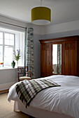 Wooden wardrobe in Devon bedroom with checked blanket on bed