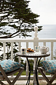 Table and chair with cushions on balcony of Devon home