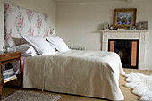 Floral headboard on bed with towelling cover in room with original fireplace in Rye, Sussex