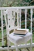 Nahaufnahme eines aufgeschlagenen Buches auf einem verzierten Polsterstuhl auf überdachtem Balkon