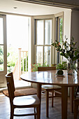 Wood dining table and chairs with open door to sunlit garden in Arundel, West Sussex