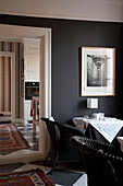 Black painted cane furniture at dining table with oversized mirror
