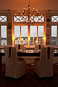Esstisch mit Kronleuchter und brennenden Kerzenleuchtern am Fenster mit Blick auf Mariefred, Schweden