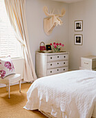 Chest of drawers facing double bed in neutral colour bedroom