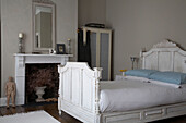 Double bed with carved wooden headboard next to fireplace