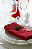 Christmas themed place setting with twig wrapped in red napkin