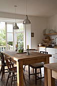 Ceiling light suspended above wooden table and chairs in centre of kitchen