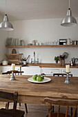 Ceiling light suspended above wooden table and chairs in centre of kitchen