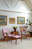 Rosa und floral gemusterte Stühle in einem weißen Wohnzimmer mit Kunstwerken