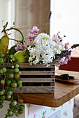 Cut flowers and unripe tomatoes in a wooden vegetable box