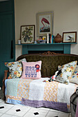 Quilted blanket and cushions on antique sofa across fireplace