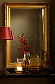 Red lamp with gilt mirror frame and Christmas berries