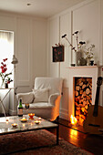 Guitar at fireplace with lit candle in room with white armchair