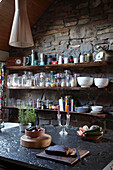 Textured worktop and open shelving in farmhouse kitchen with exposed stone