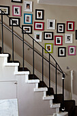 Family photographs on staircase in home of London fashion designer