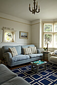 Light blue sofa with cream cushions and blue patterned rug in Norfolk beach house, UK