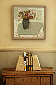 Books on side table below artwork in Brighton home, UK