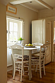White painted chairs at table in West Sussex home, England, UK