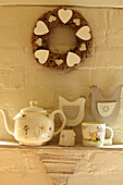 Heart shapes on floral wreath with tea set on shelf in West Sussex home, England, UK