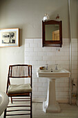 Sockelwaschbecken und Klappstuhl im Badezimmer eines Hauses in Brighton, East Sussex, England, UK