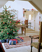 A traditional hallway decorated for Christmas tree with decorations presents stone floor rug side table