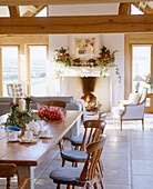 Weihnachtlich geschmücktes traditionelles Esszimmer im Landhausstil mit Steinkamin, Balkendecke, Polsterstuhl und Esstisch mit Holzstühlen