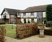Overview of the exterior and front garden of a large traditional style converted timber framed country house and barn