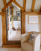Detail of a modern leather armchair and a timber framed doorway leading to a bathroom
