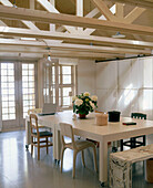 Country style dining room with exposed wooden beams above a contemporary dining table