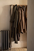Coats and scarves hanging from hooks next to old fashioned radiator in hallway