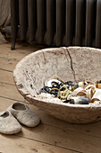 Collection of jewellery in rustic wooden bowl on wooden floor