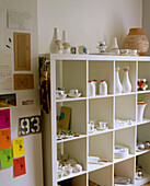 A detail of a modern kitchen shelving unit with display of white ceramic pieces Notice board