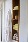 Detail of bathroom with built in shelves with bathroom towels and toilet rolls