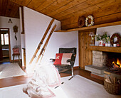 A country sitting room with a stone fireplace lit fire timber ceiling leather chair