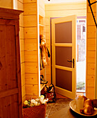 A detail of a country hallway of a wooden chalet front door open wood panelling