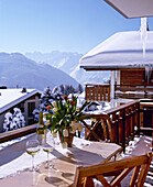 Außenansicht eines schweizer Chalets mit Weingläsern auf einem Tisch auf dem Balkon