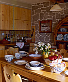 Kitchen with exposed stone walls and pine cupboard units and table set for meal