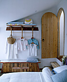 Single bed in child's bedroom with clothes hanging from hooks