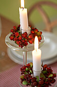 Detail eines weihnachtlich gedeckten Tisches, Kerzenständer aus Glas mit Blumen und brennenden Kerzen