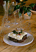 Detail of a piece of traditional Christmas cake on a white plate covered by wire mesh on a wooden surface