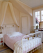 White iron bed frame with fabric canopy and pink bedcover