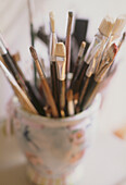 Close up details of a pot full of a variety of paintbrushes