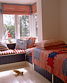 Childs red bedroom with single bed next to window seat