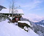 Außenansicht eines schneebedeckten Schweizer Chalets in den Bergen